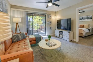 A living room with a leather sofa, a coffee table, a TV, and a balcony with sliding doors. - Near Central Dtwn Flagstaff! Chic Condo (Flagstaff)