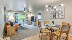 Un coin repas avec une table en verre et des chaises en bois, un ventilateur de plafond et un luminaire fixé au mur.