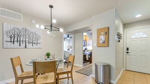 Un coin repas comprenant une table ronde, quatre chaises, un luminaire au plafond et un tableau accroché au mur.