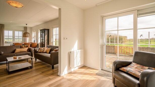 A spacious living room with a large window, a fireplace, and a cozy seating area. - Tastefully Furnished Holiday Home (De Koog)