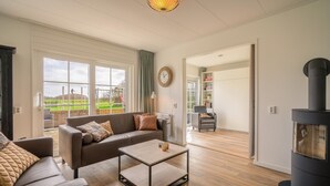 A spacious living room with a sofa, coffee table, and a fireplace. - Tastefully Furnished Holiday Home (De Koog)