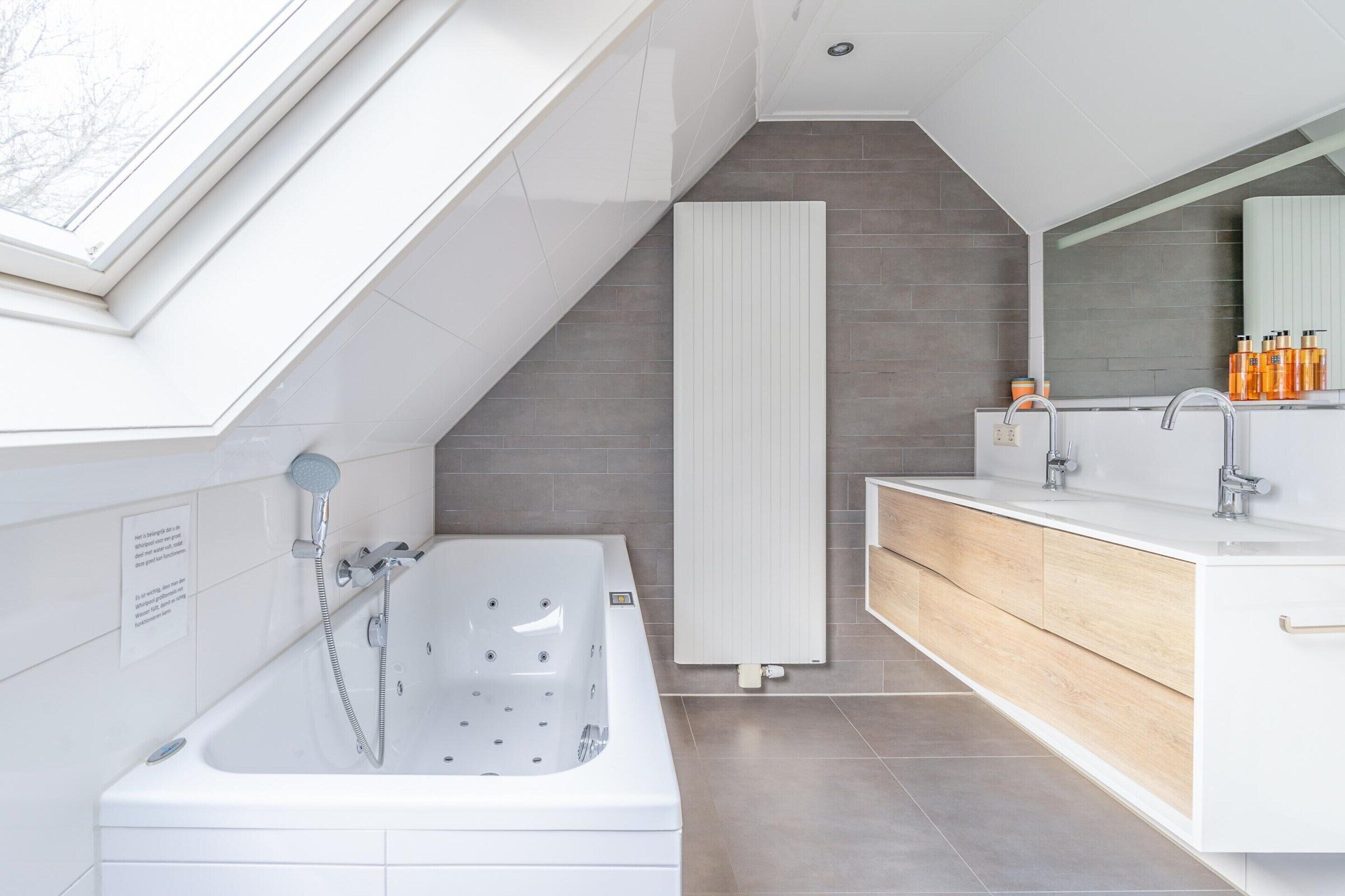 Une salle de bain moderne avec une baignoire sur pieds, un grand miroir et un meuble-lavabo avec un évier et des rangements.