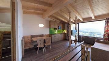 Interior de madera con comedor, cocina y balcón con vistas.