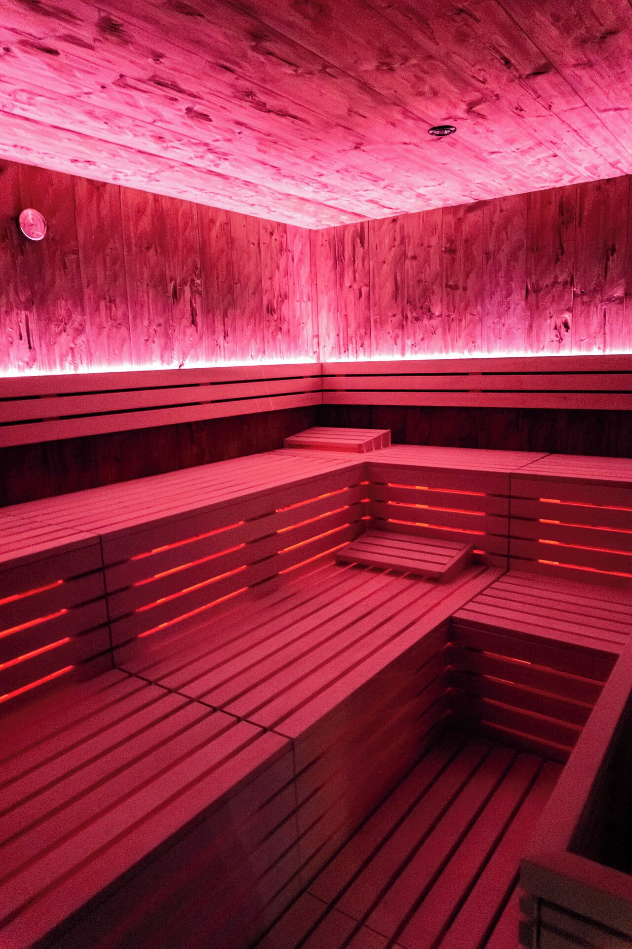 Una sauna amb seients de fusta i il·luminació vermella.