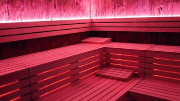 Una sauna amb seients de fusta i il·luminació vermella.