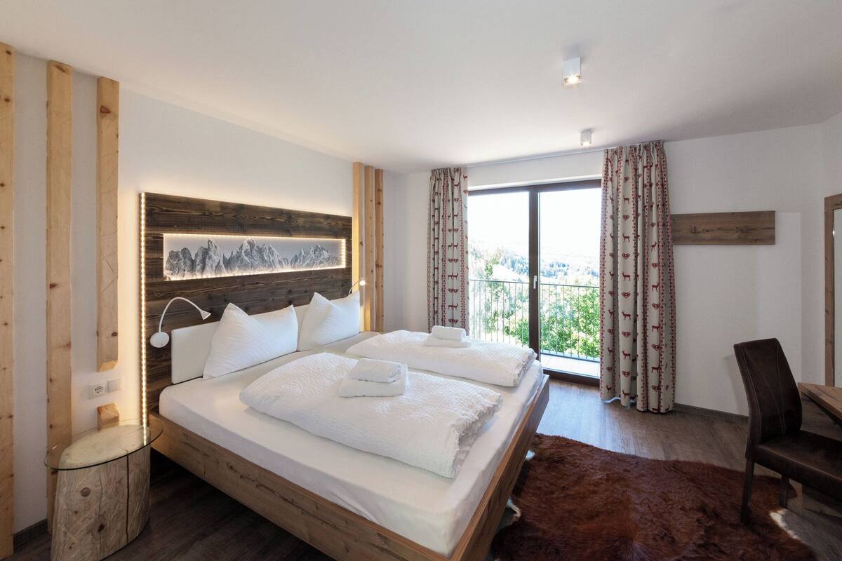 A modern hotel room with a large bed, wooden headboard, and a view of the outdoors.
