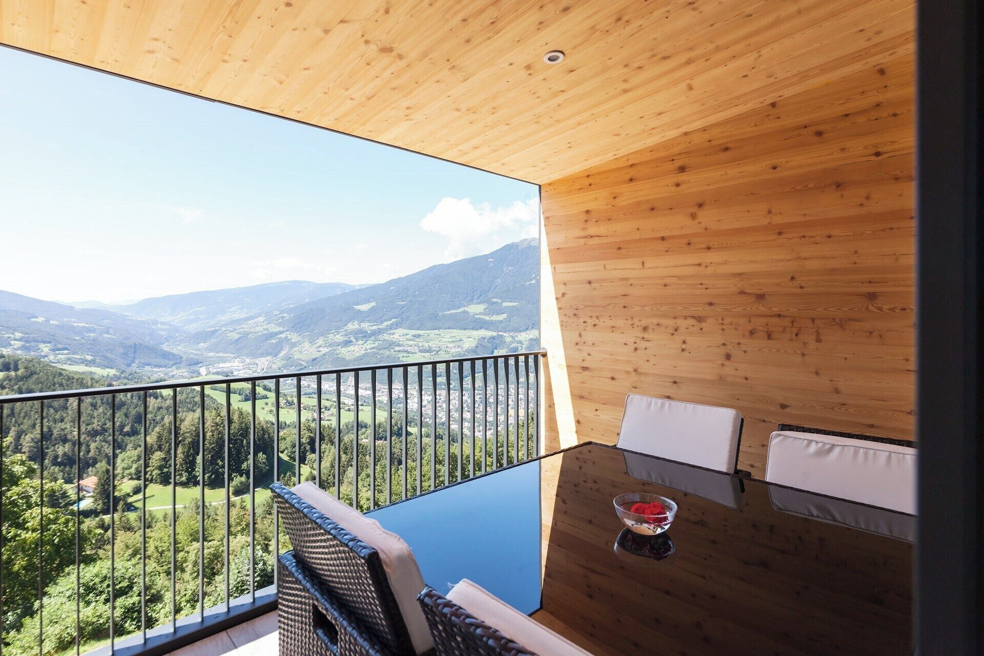 A balcony with a wooden ceiling and a glass floor, overlooking a mountainous landscape.