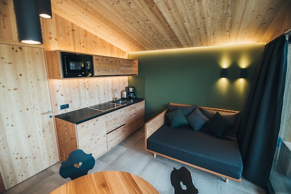 A compact room with a kitchenette, a bed, and a dining area.