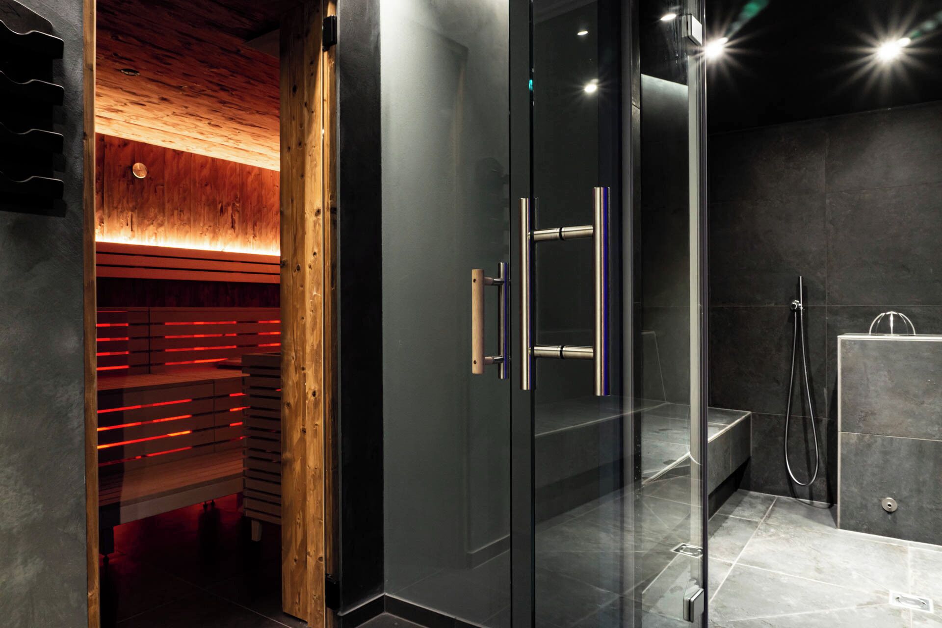 A modern bathroom with a glass shower enclosure, a wooden bench, and a heated floor.