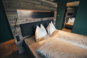 Een moderne slaapkamer met een houten hoofdbord, een grote spiegel en een opgemaakt bed met witte lakens.