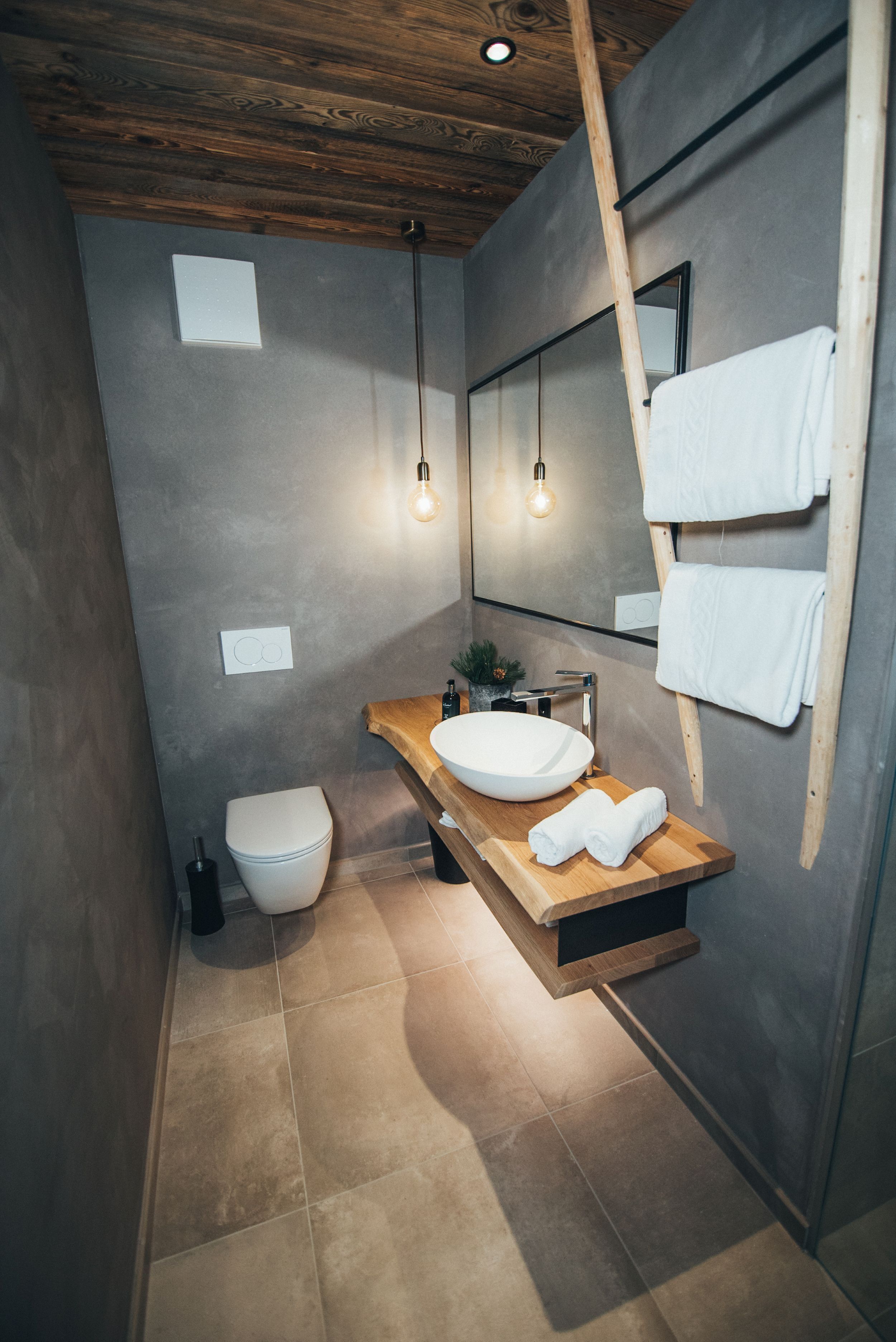 Une salle de bain moderne avec un meuble-lavabo en bois, un grand miroir et un porte-serviettes.