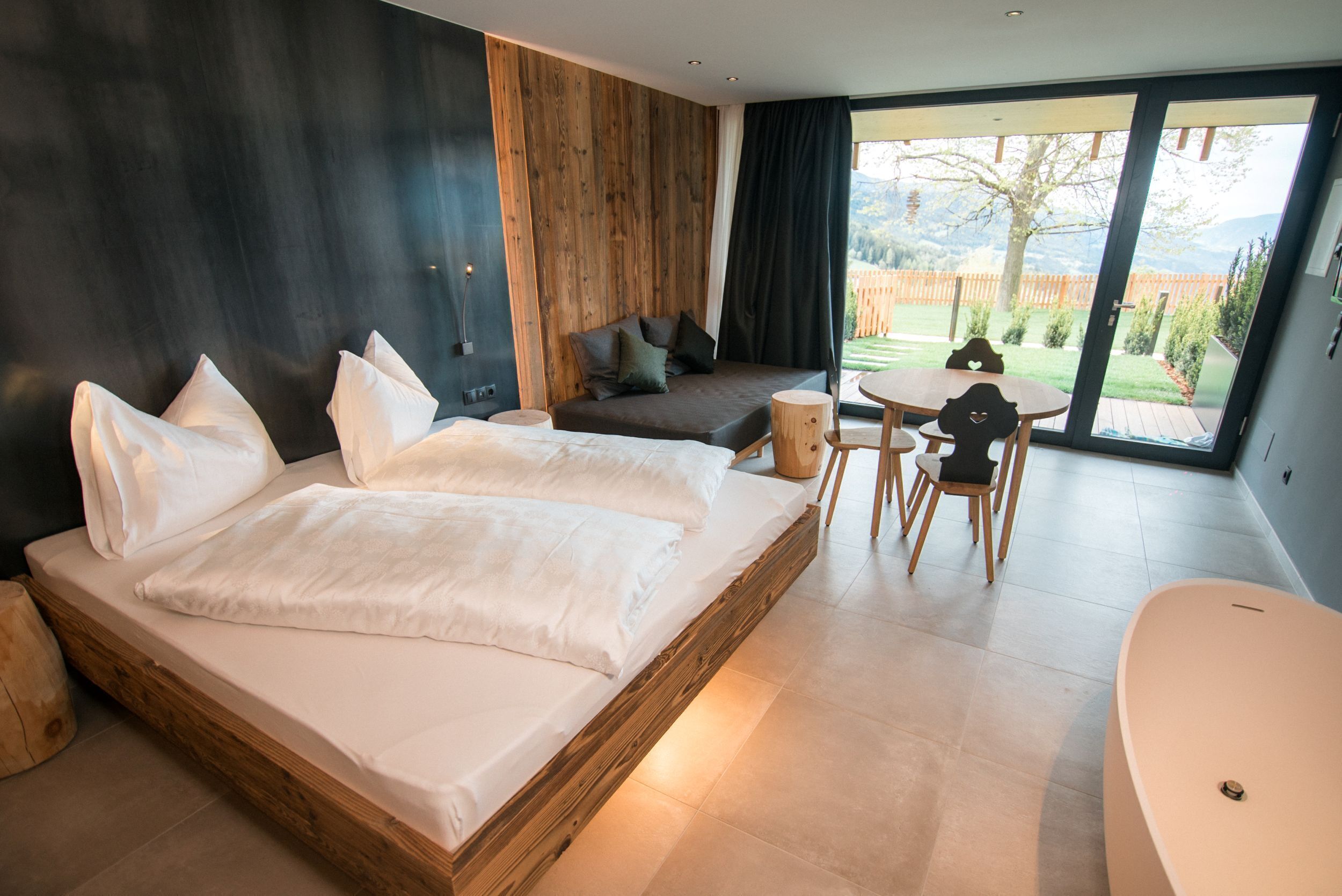 Ein modernes Schlafzimmer mit einem großen Bett, einer Couch, einem runden Tisch und einer Badewanne.