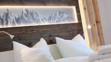 A bedroom with a wooden headboard, white pillows, and a framed mountain landscape picture.