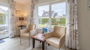 A room with two leather chairs, a small table, a lamp, and a window with curtains. - Charming Villa Near the sea and Forest (De Koog)
