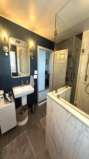 A modern bathroom with a large mirror, a sink, and a shower area.