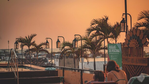 A poolside area with steps leading down to the water, palm trees, and a sign indicating pool rules. - KIM  (Cartagena)