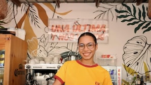 A person standing behind a counter with a coffee machine and various kitchen items. - KIM  (Cartagena)