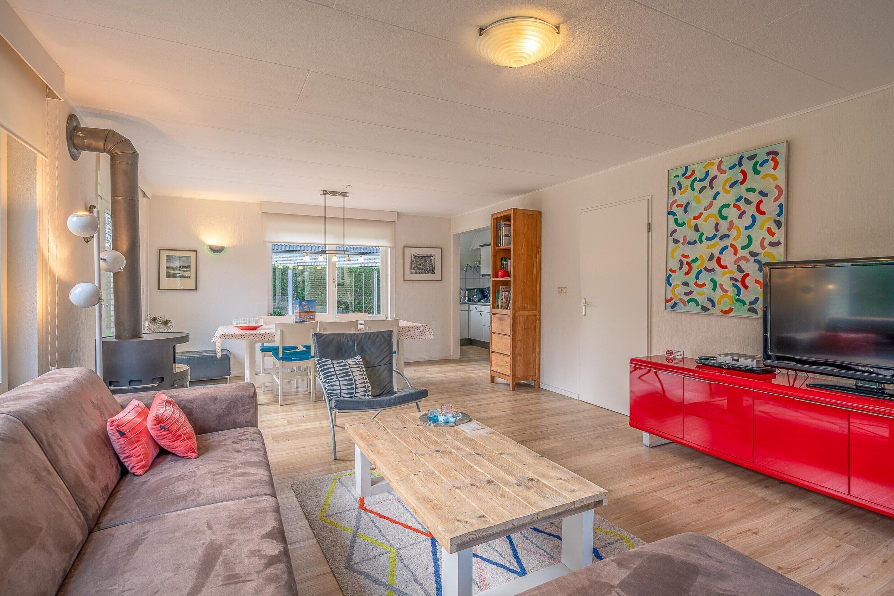 A modern living room with a sofa, coffee table, and red entertainment unit.