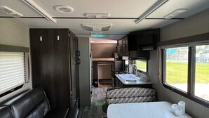Interior compacto de una caravana con kitchenette, comedor y litera.