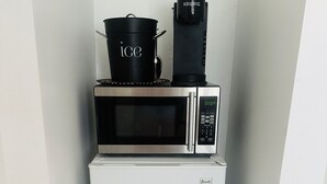 Une cuisine de taille réduite, avec un réfrigérateur blanc, un four à micro-ondes et une machine à café posée sur le dessus.