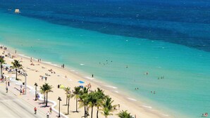 A beach with clear turquoise waters, palm trees, and people enjoying the sun and sea. - Wilton Manors Guesthouse #1 (Wilton Manors)