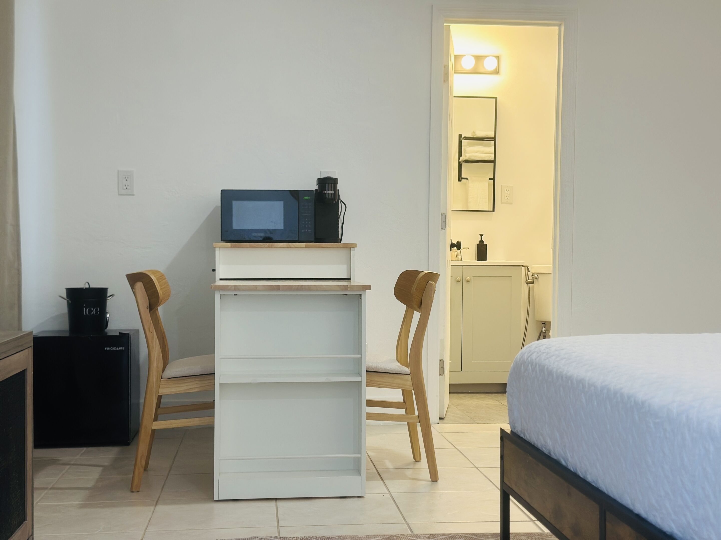A compact room with a bed, a small kitchenette with a microwave, a coffee maker, and a cabinet.