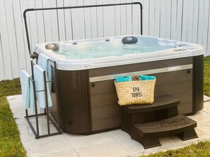A spa hot tub with a wooden exterior, a towel rack, and a spa towel bag attached to the side.