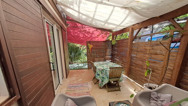 A patio area with a table and chairs, a cushioned seating area, and a wooden fence.