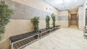 Un vestíbulo con suelo de mármol, una fila de bancos y plantas en macetas.