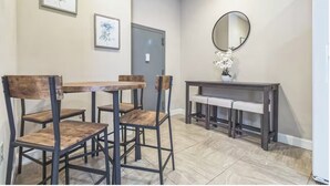 Un comedor con una mesa y sillas de madera, un banco, un espejo y cuadros en la pared.
