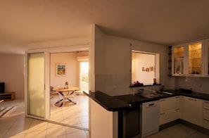 A modern kitchen with a black countertop, white cabinets, and a dishwasher. - Ocean View, Luxury Apartment in Trois Ilets (Les Trois-Îlets)