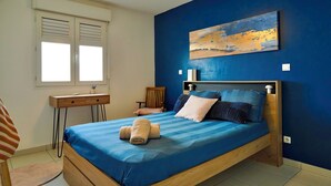 Une chambre à coucher comprenant un lit, un bureau, une chaise et un ventilateur de plafond.