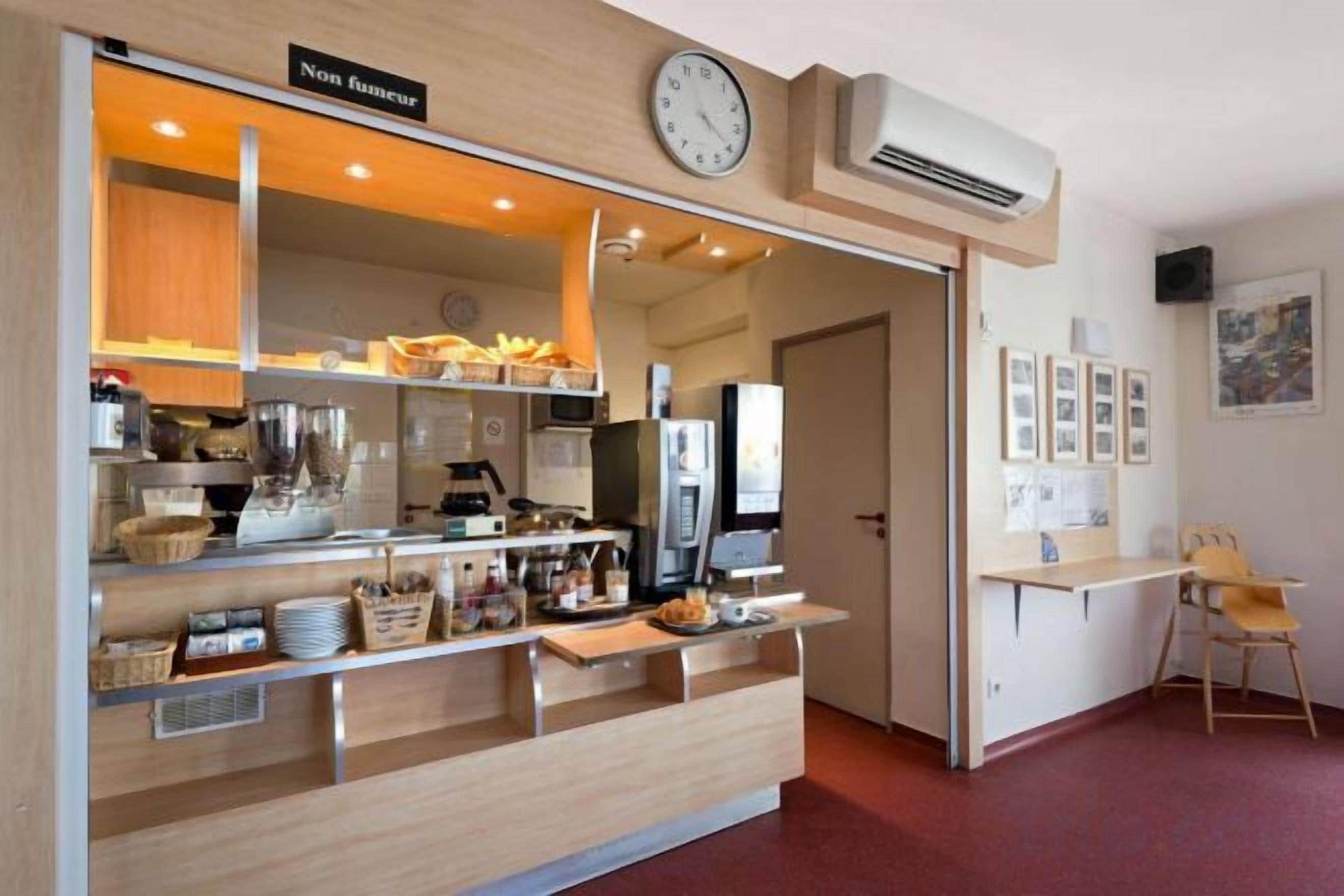A café with a counter, shelves with food items, a clock, and a chair.