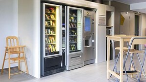 A modern interior with vending machines, a wooden chair, and a foldable table. - B&B Hotel Valence Sud (Valence)