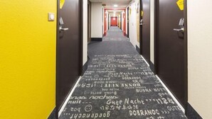A hotel hallway with a carpet featuring various phrases in multiple languages. - B&B Hotel Valence Sud (Valence)