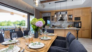 Une cuisine moderne avec des meubles en bois, un pare-feu en marbre et un coin repas avec une table en bois mise pour le repas.