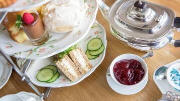 Ett elegant teservis med flera våningar, serverat med smörgåsar, skivor av gurka och sylt.