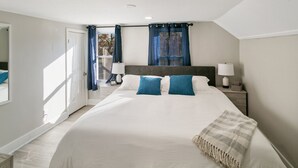 Quarto com cama grande, duas mesas de cabeceira, janela com cortinas e vista para o exterior.