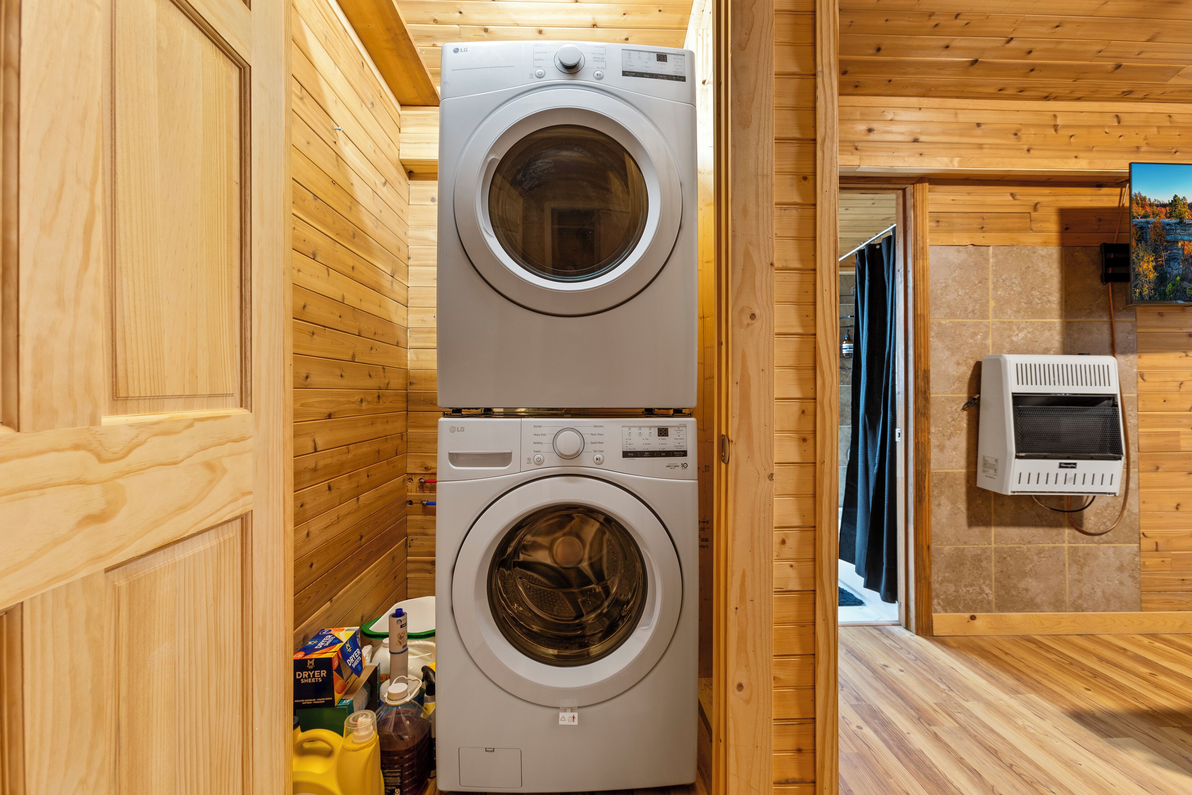 Une buanderie équipée de deux machines à laver superposées, d’un sèche-linge et d’un mur carrelé orné d’un tableau.