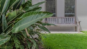 A bench in front of a building with large windows and a well-maintained lawn. - Barrels (kingscliff)