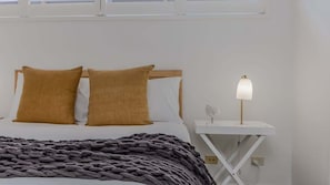 A bed with two pillows, a bedside lamp, and a blanket. - Barrels (kingscliff)