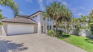 A two-story house with a garage, a well-maintained lawn, and a large tree. - Barrels (kingscliff)