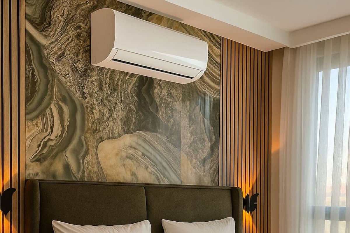 A hotel room with a large bed, a marble wall, and an air conditioning unit above it.