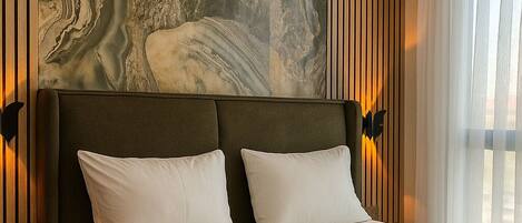 A hotel room with a large bed, a marble wall, and an air conditioning unit above it.