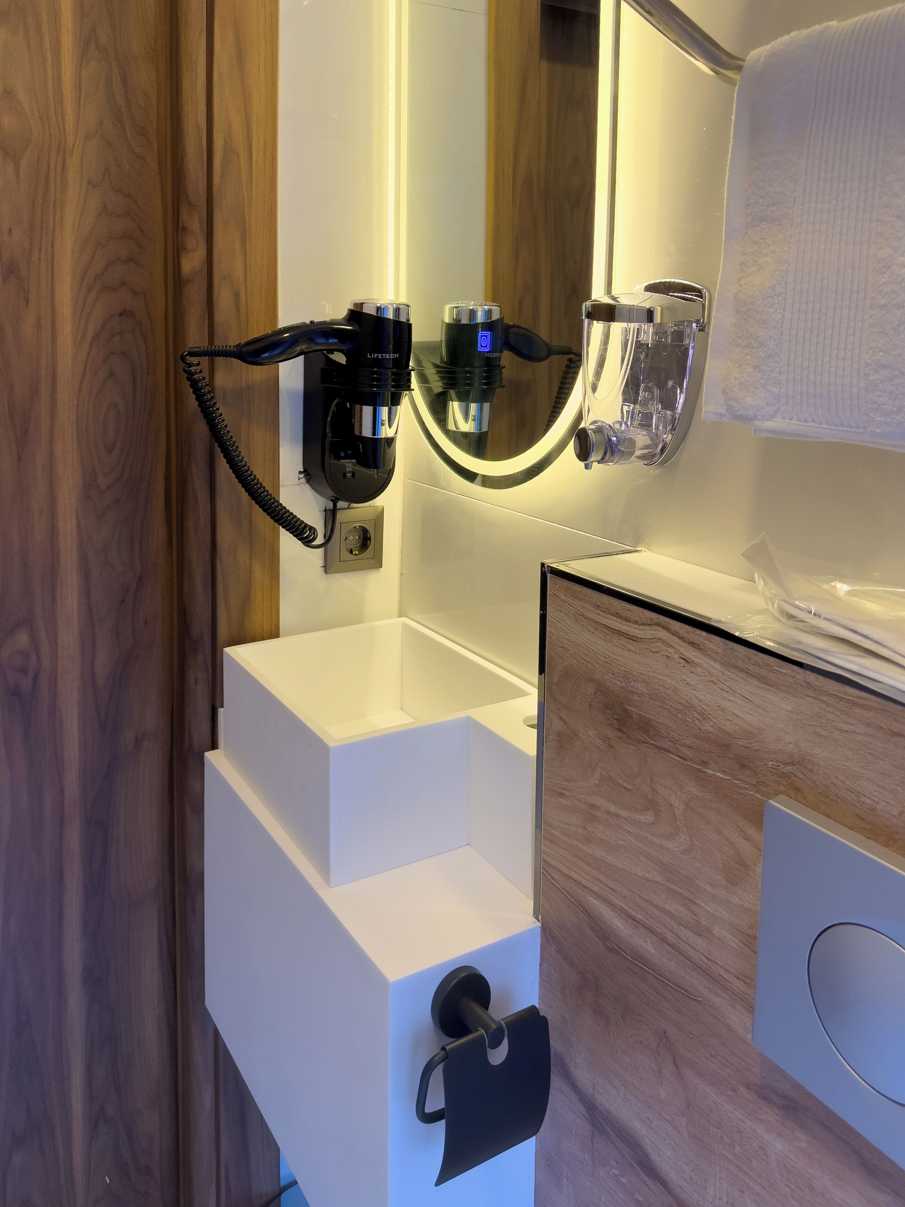 Une salle de bain moderne avec un lavabo blanc, un miroir et un porte-serviettes.