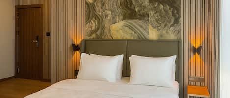 A hotel room with a large bed, a wooden door, and a wall with vertical stripes and a marble-like design.