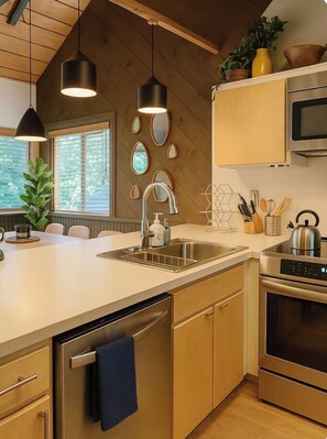 A modern kitchen with a central island, stainless steel appliances, and a wooden ceiling. - Cozy Ski Condo! Giant Hot Tub, EV Garage - Walk to the Village (Mammoth Lakes)