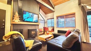 A cozy living room with a fireplace, a television, and a comfortable seating area. - NEW & FUN! Hot Tub, EV Outlet in Garage (Mammoth Lakes)