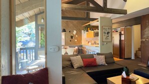 A modern living room with a sofa, a coffee table, and a basket. There is a kitchen area in the background with a dining table and chairs. - NEW & FUN! Hot Tub, EV Outlet in Garage (Mammoth Lakes)