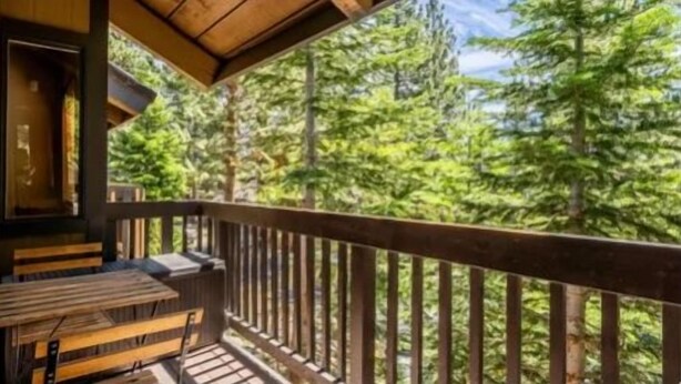 A wooden deck with benches, overlooking a forested area.